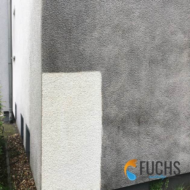 Die gereinigte Probefläche auf einer dunkelgrauen Putzfassade offenbart, dass es sich eigentlich um eine weiße Fassade handelt.